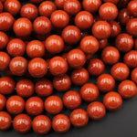 May include: A close-up image of a strand of round, red gemstone beads. The beads are smooth and polished, with a slight sheen. The beads are arranged in a random pattern, creating a visually appealing texture.