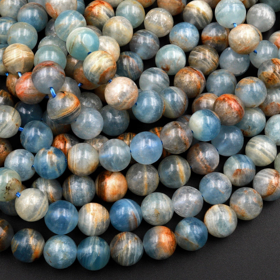 May include: A close-up of a strand of blue and brown agate beads. The beads are round and have a smooth, polished finish. The beads are arranged in a random pattern, creating a visually appealing texture.