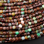 May include: Close-up of a strand of brown, green, and white gemstone beads. The beads are square-shaped and have a rough, textured surface. The beads are arranged in a random pattern, creating a visually appealing and unique look.