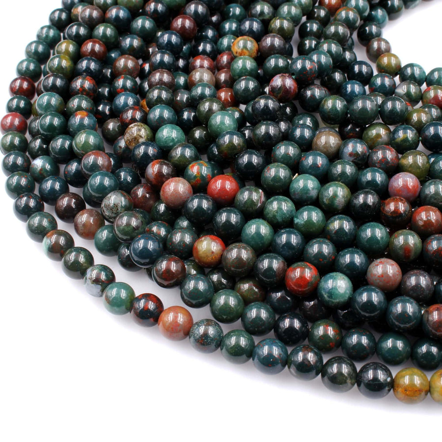 May include: A strand of green, red, and brown round gemstone beads. The beads are smooth and polished. The beads are arranged in a circular pattern.