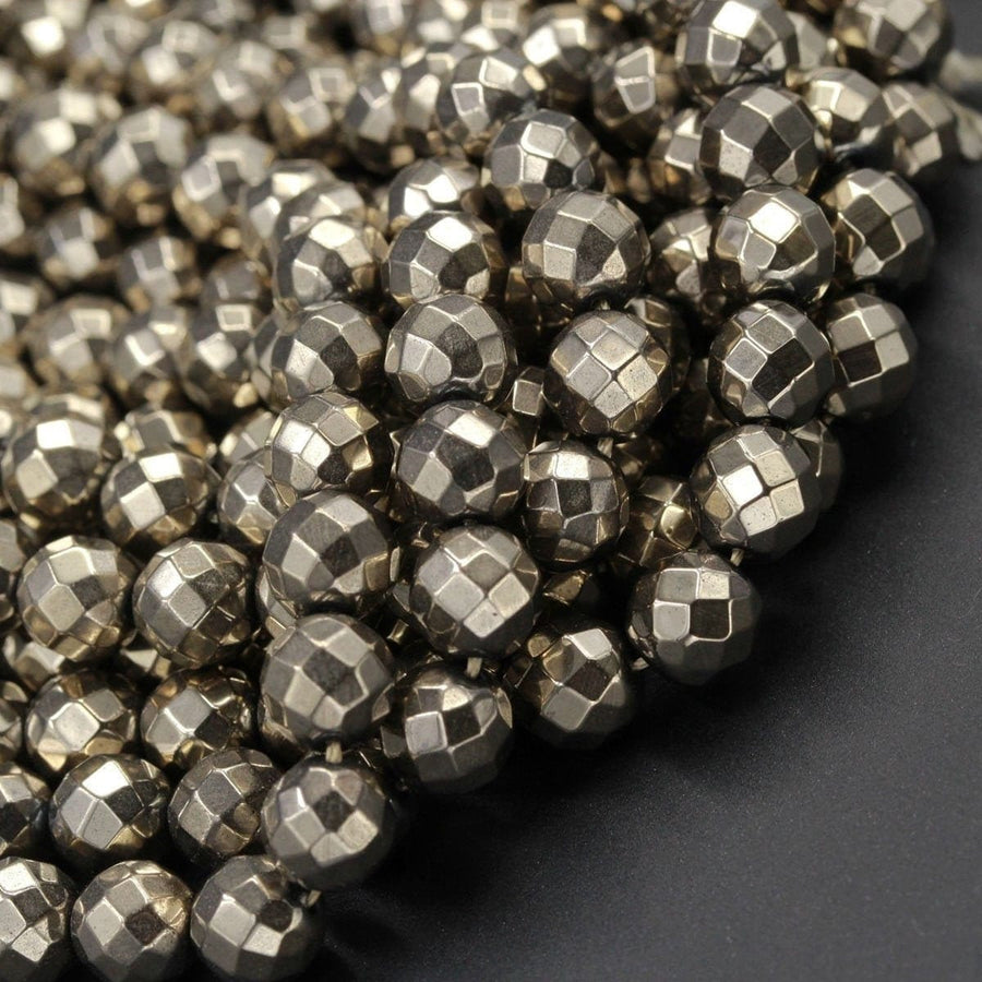 May include: A close-up of a pile of silver faceted gemstone beads. The beads are round and have a metallic sheen.
