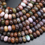 May include: A close-up of a strand of brown, green, and purple agate beads. The beads are round and have a smooth, polished finish. The beads are arranged in a random pattern, creating a visually appealing and unique look.