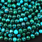 May include: A close-up of a collection of round, green and blue gemstone beads. The beads have a marbled pattern with swirls of green and blue. The beads are arranged in a random pattern, creating a visually appealing texture.