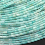 May include: A strand of light blue aquamarine gemstone beads. The beads are rectangular and have a smooth, polished finish. The beads are arranged in a row, with the ends of the beads overlapping slightly. The beads are all the same size and shape.