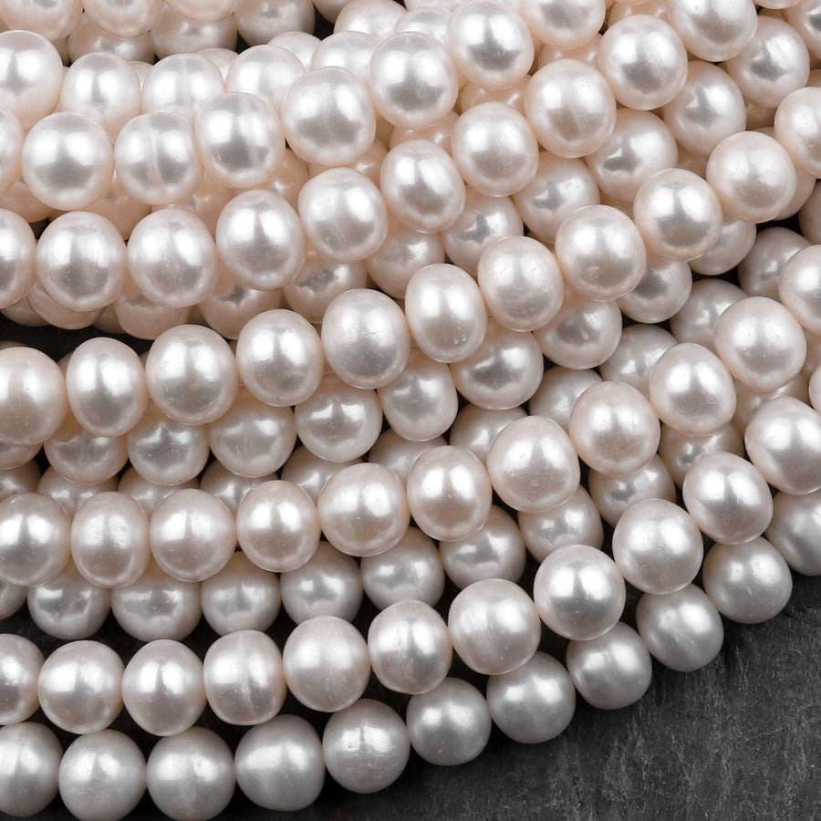 May include: A close-up image of a strand of white pearls. The pearls are round and smooth, and they are arranged in a random pattern. The pearls are all the same size and shape, and they have a high luster.