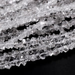 May include: A strand of clear quartz crystal beads. The beads are faceted and have a rough, natural look. The beads are strung on a white thread.