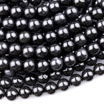 May include: A close-up image of black round beads. The beads are smooth and shiny, with a slight sparkle. The beads are arranged in a pile, with some overlapping.