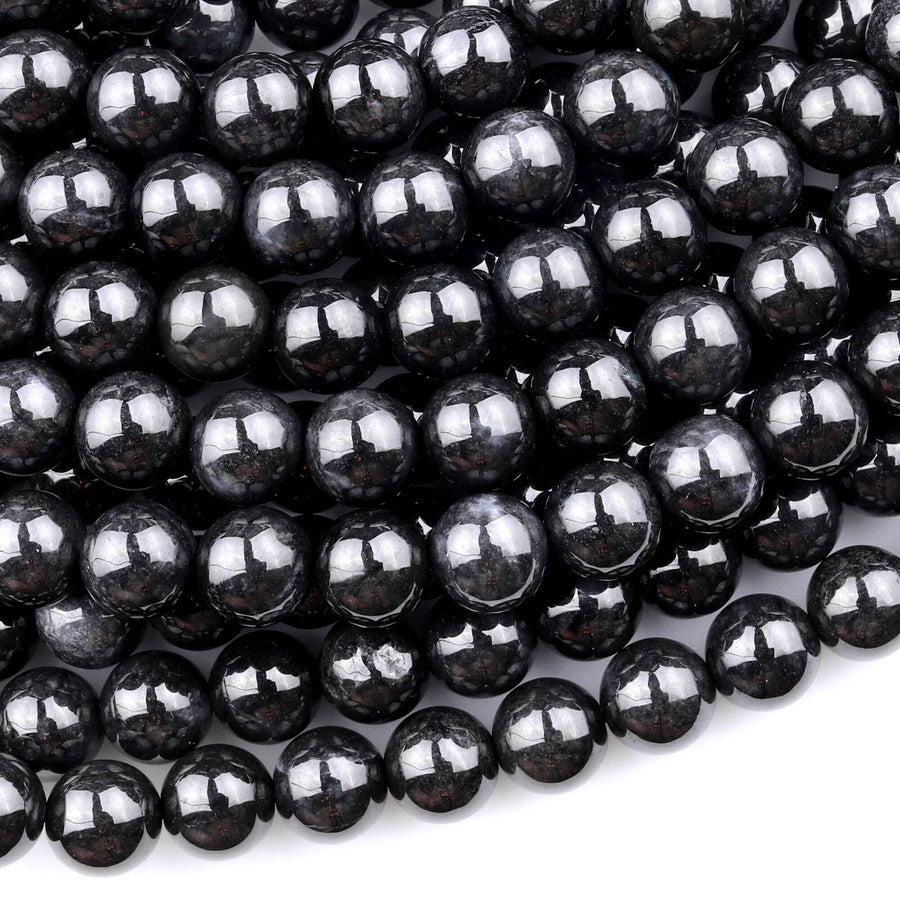 May include: A close-up image of black round beads. The beads are smooth and shiny, with a slight sparkle. The beads are arranged in a pile, with some overlapping.
