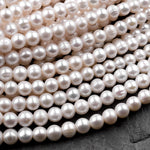 May include: A strand of white pearl beads. The pearls are round and smooth, and they are arranged in a close-up view. The pearls are all the same size and shape, and they are strung together on a thin, white thread.