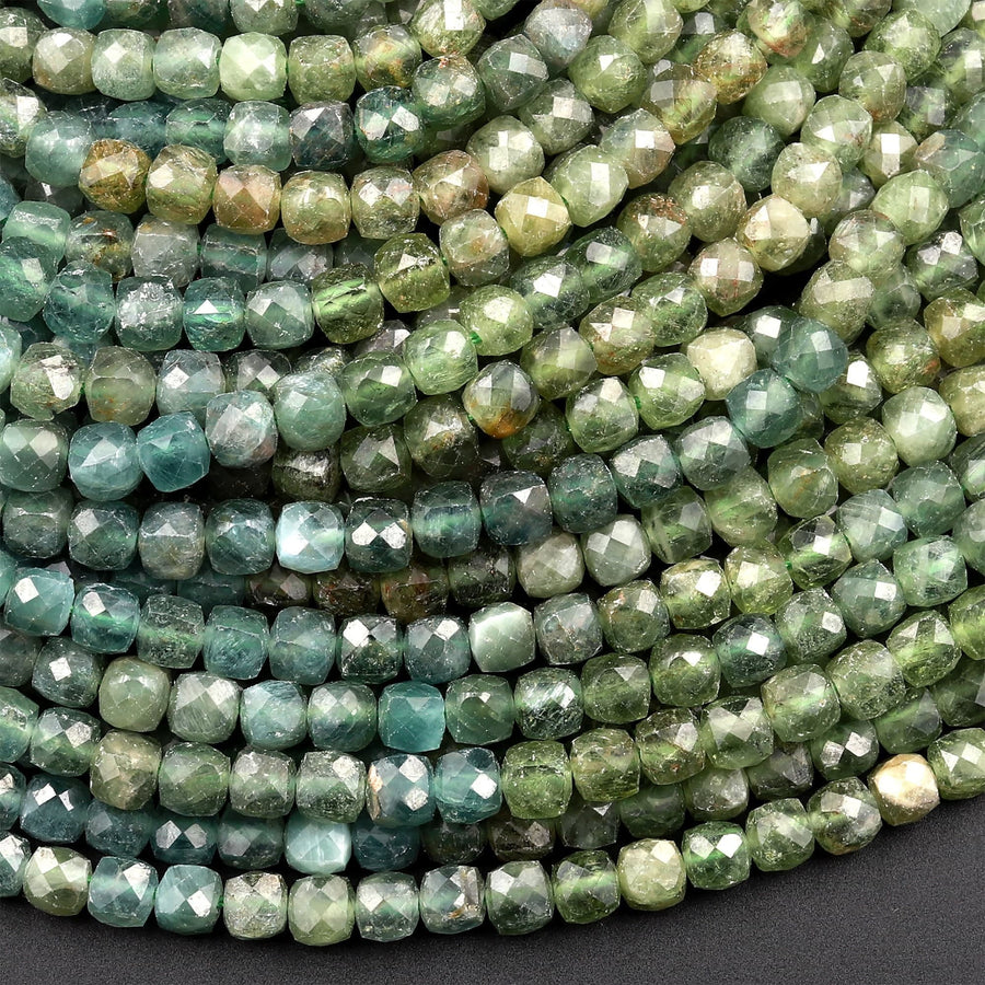 May include: A strand of green faceted gemstone beads. The beads are a light green color with a slightly darker green hue. The beads are all uniform in size and shape.