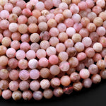 May include: A strand of pink opal beads, each bead is faceted and has a light pink color with white and brown inclusions. The beads are strung on a thin red thread.