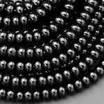 May include: A close-up of a pile of black hematite beads. The beads are round and smooth, and they have a shiny, metallic finish.
