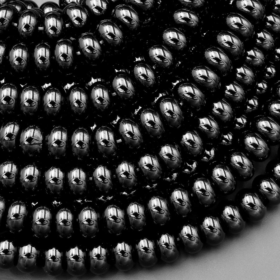May include: A close-up of a pile of black hematite beads. The beads are round and smooth, and they have a shiny, metallic finish.