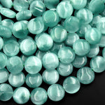 May include: A close-up of a strand of round, light blue and green gemstone beads. The beads are smooth and have a slight sheen. The beads are arranged in a random pattern.
