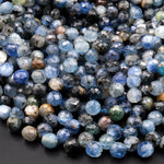 May include: A close-up of a pile of blue kyanite gemstone beads. The beads are faceted and have a variety of shades of blue, from light to dark. Some beads have a cloudy or milky appearance, while others are more translucent. The beads are arranged in a random pattern, creating a visually appealing texture.