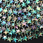 May include: A collection of iridescent star-shaped beads. The beads display a range of colors including teal, purple, and gold. Each bead has a five-point star shape with a glossy, reflective surface. The beads are scattered, creating a dense, textured pattern. These beads are suitable for jewelry making or craft projects.