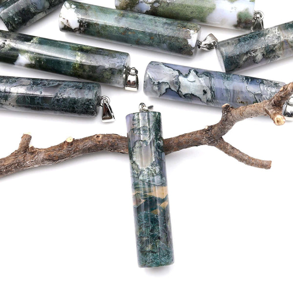 May include: A collection of green, gray, and white agate stone pendants with silver jump rings. The pendants are cylindrical in shape and have a variety of patterns and textures. The pendants are displayed on a branch against a white background.