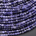 May include: Close-up of a collection of faceted, square-shaped beads in shades of deep purple and lavender. The beads are strung together, creating a textured surface. The beads are likely used for jewelry making.