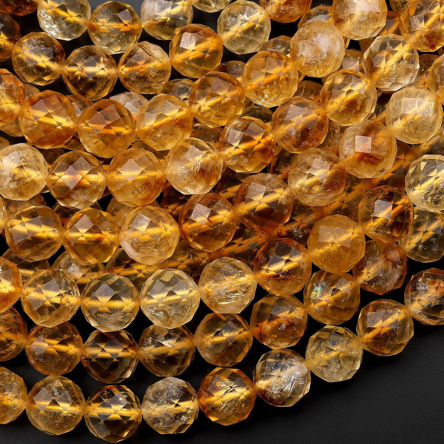 May include: A close-up of a strand of faceted citrine beads. The beads are a warm, golden yellow color and have a smooth, polished finish.