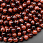 May include: A strand of red tiger's eye beads. The beads are round and have a smooth, polished finish. The red tiger's eye is a gemstone that is known for its unique chatoyancy, which is the shimmering effect that is visible when the stone is turned in the light.
